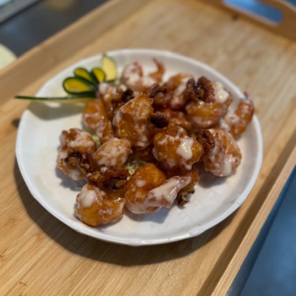 Sweetspot's crispy fried shrimp with creamy white sauce and candied walnuts on a white plate.